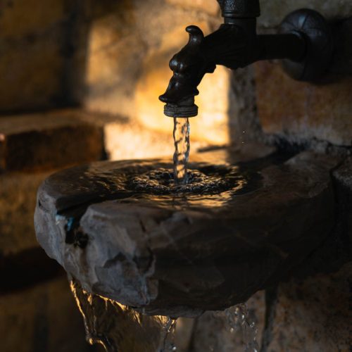 An old stone faucet with fresh water at Vintage Stone House in Argolida, Greece